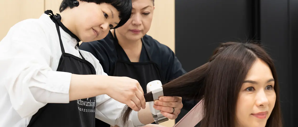Two hair care professionals treat a consumer’s hair with the SalonLab Smart Analyzer.