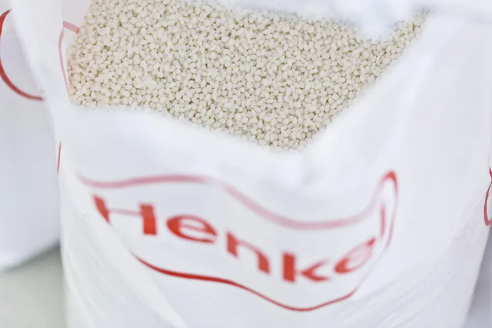 Close-up of a white, Henkel-branded bag containing white pellets.