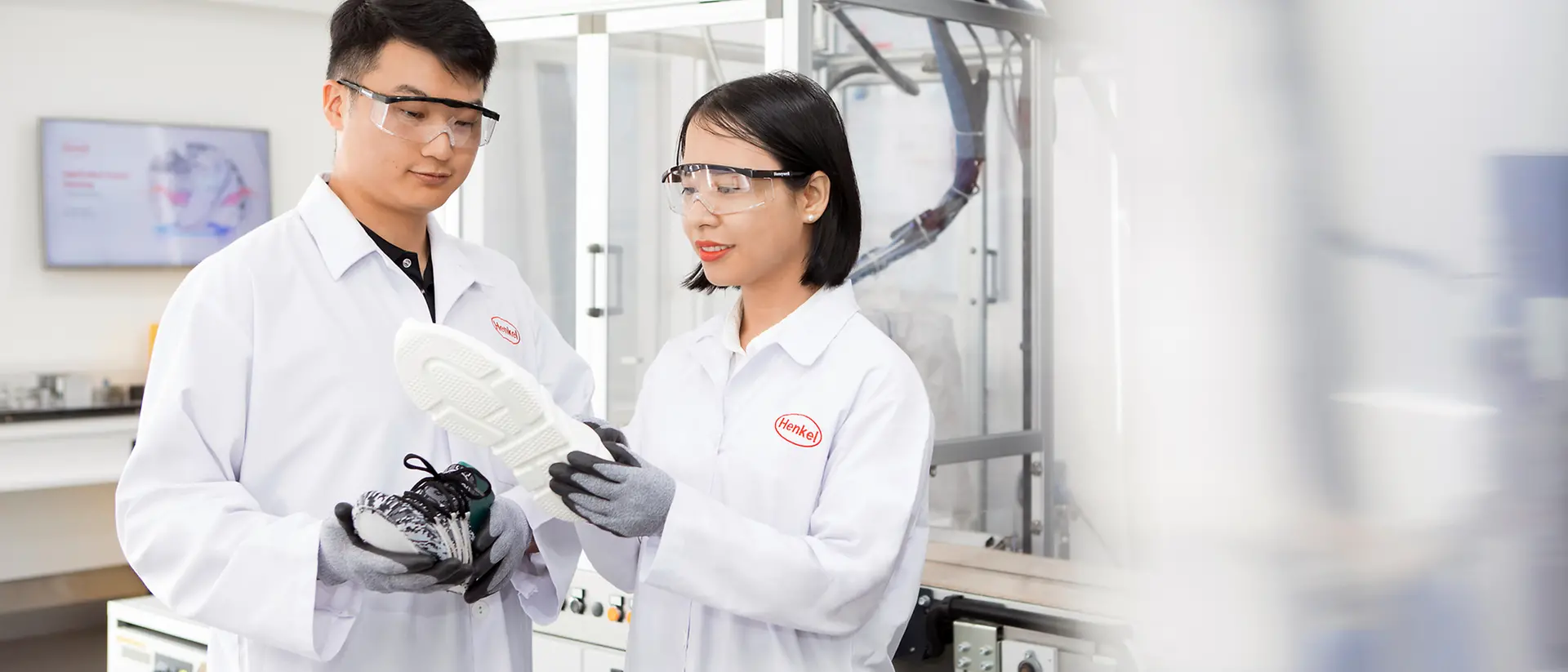 Two Henkel researchers in a laboratory analyze a shoe sole that has been bonded with innovative Henkel adhesives.