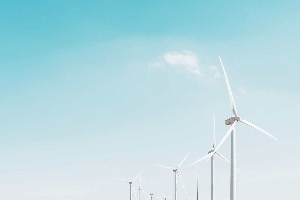 a row of wind turbines against a pale blue sky