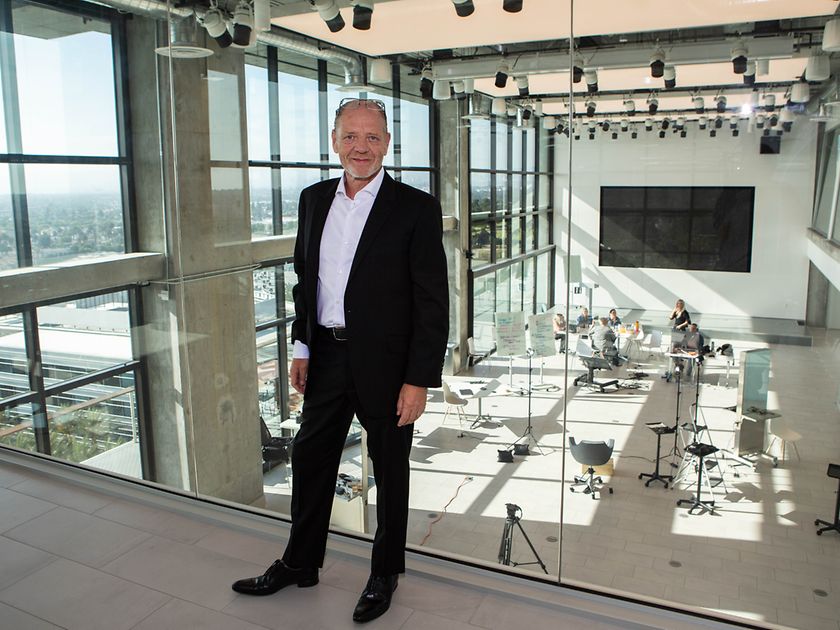 Stefan L. Mund, Regional Head Henkel Beauty Care Professional North America in front of a glass wall with view of a seminar room with people