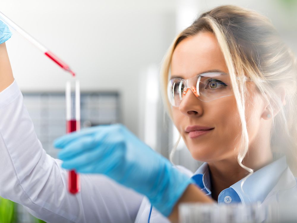 A lady is standing at the laboratory hood is working with a pipette, representing our analytical topics at Corporate Scientific Services.