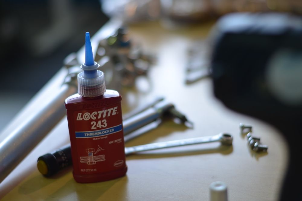 A bottle of glue between tools and screws.