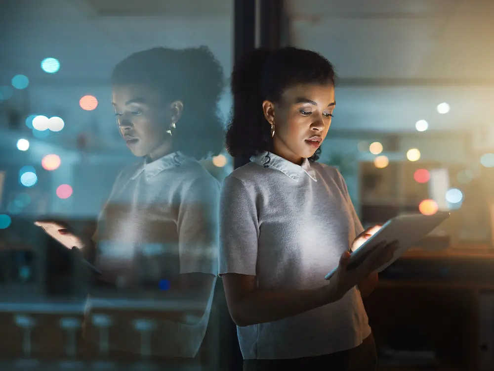 A woman is typing on a tablet, looking focused and concentrated.