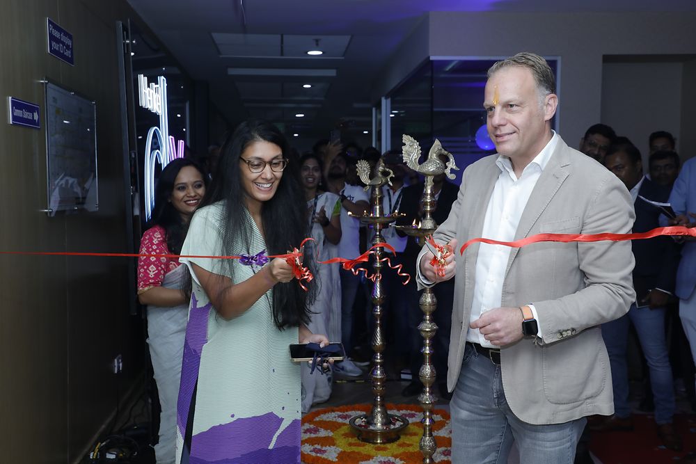 Roshni Nadar Malhotra and Michael Nilles standing in front of the crowd and cutting a red ribbon. 