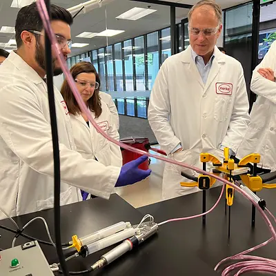 Jan-Dirk Auris (pictured right), Henkel Executive Vice-President Adhesive Technologies, observes a color-matched adhesives demonstration from Application Engineers Efren Jimenez and Burcak Conley