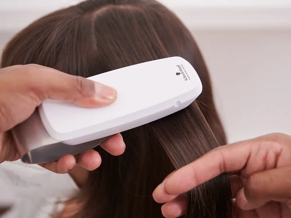 The hairdresser scans the customer's hair with the SalonLab Analyzer.