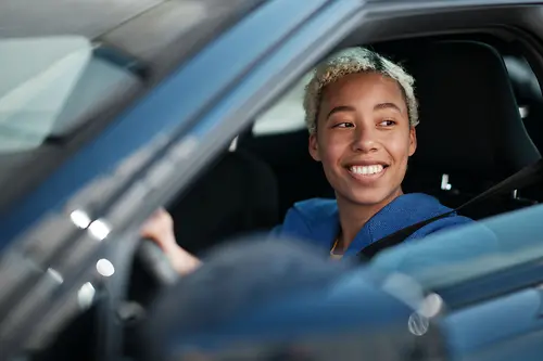 A driver sits in her e-car and smiles.