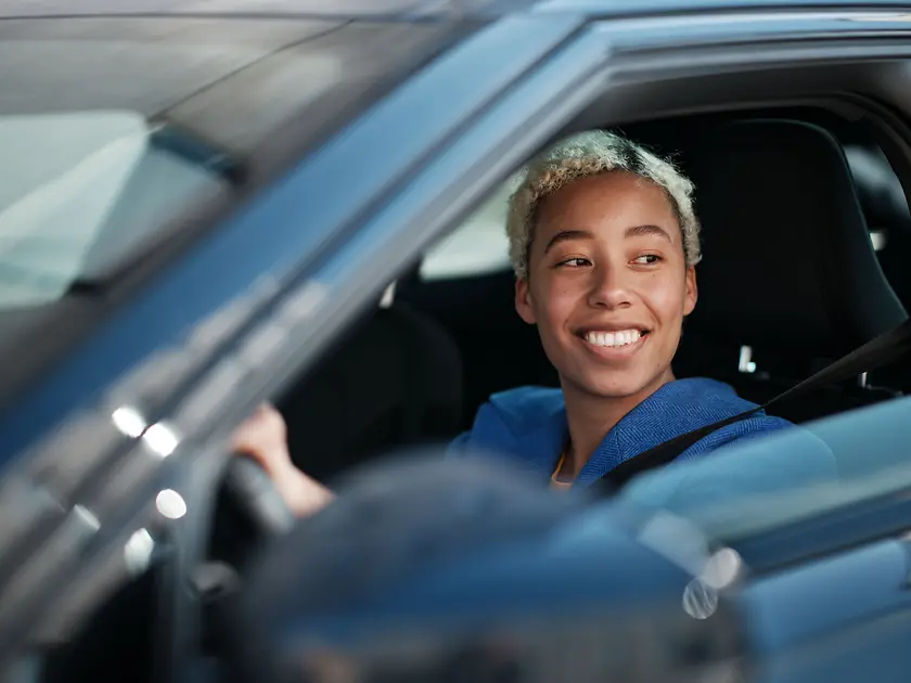 A driver sits in her e-car and smiles.
