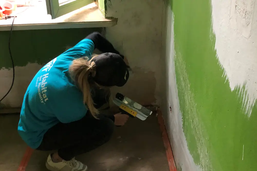 A woman is spackling a wall.