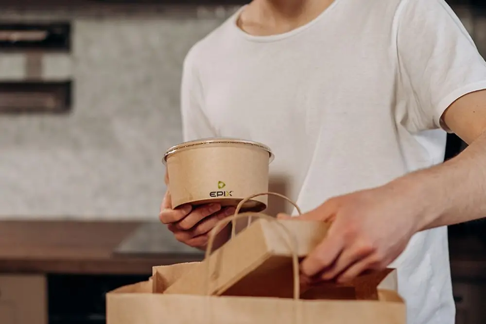 A man grabs paper two to-go-boxes out of a paper bag.