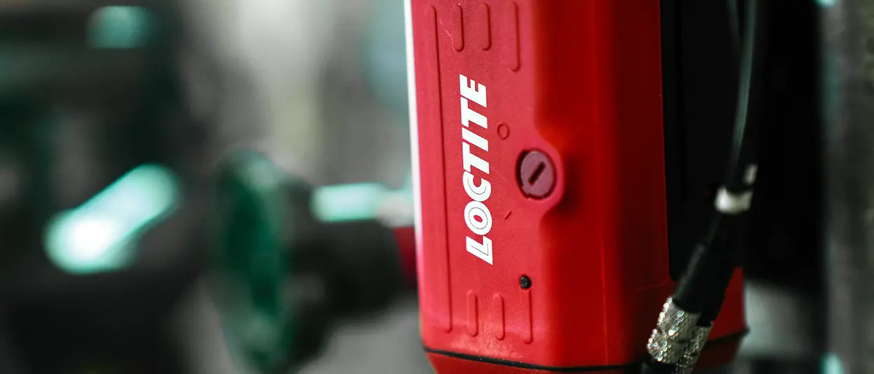 A close-up of a red Loctite PULSE device in a production site.