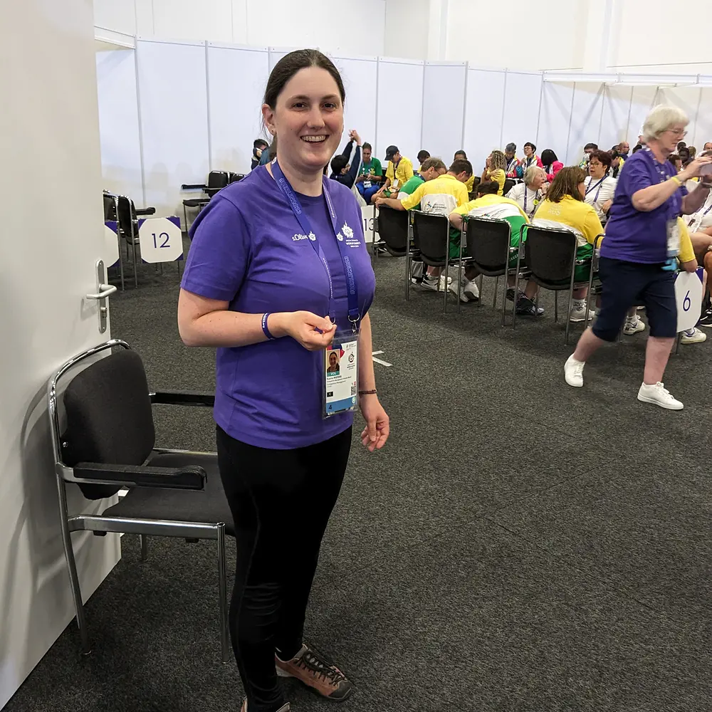 Katrin stands in one the preparation rooms for the Special Olympics athletes and smiles into the camera.
