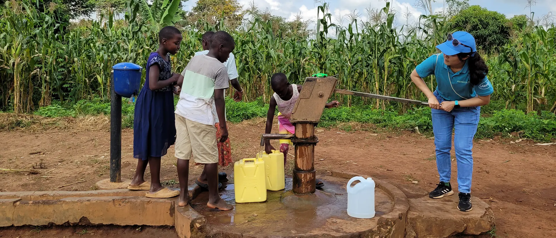 A volunteer fetches water from the pump together with the kids from the orphanages.