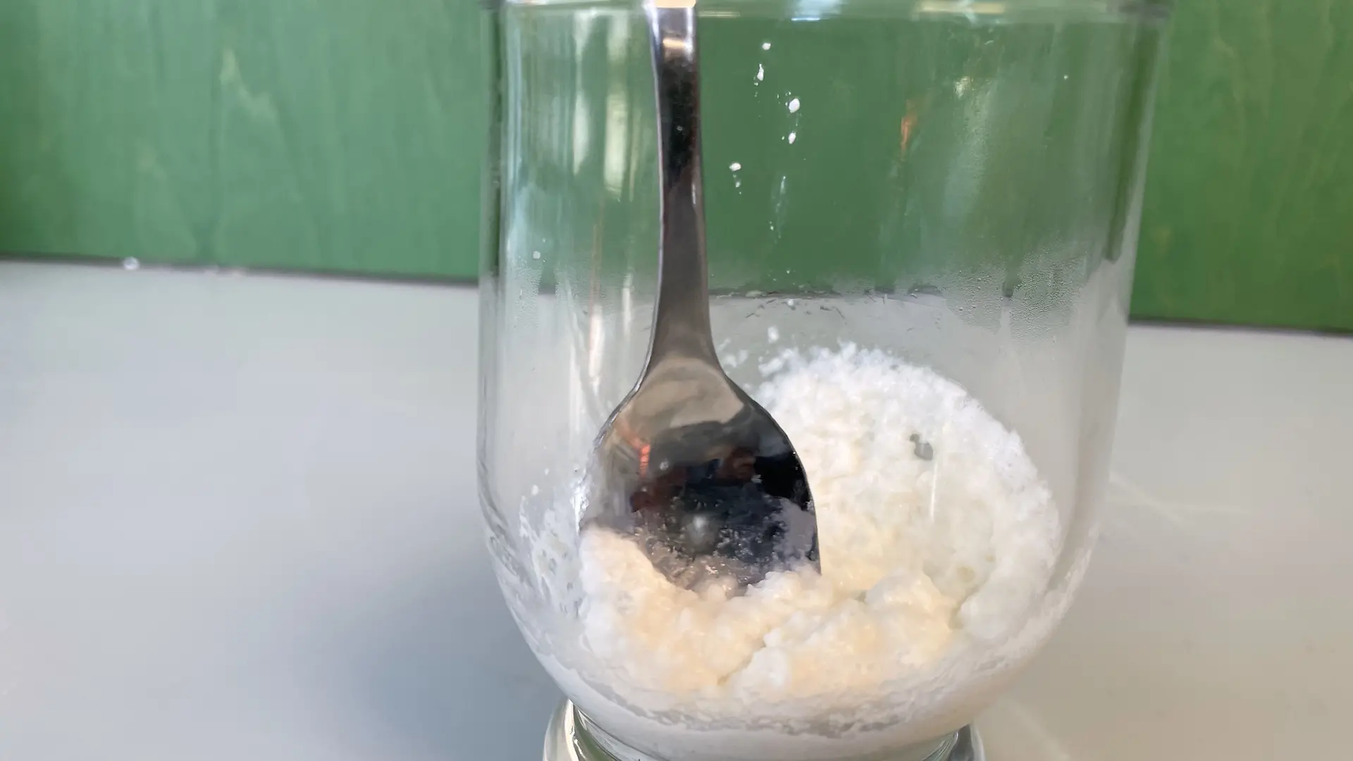 将牛奶蛋白、少量水和泡打粉倒入玻璃杯中，用勺子搅拌均匀。
