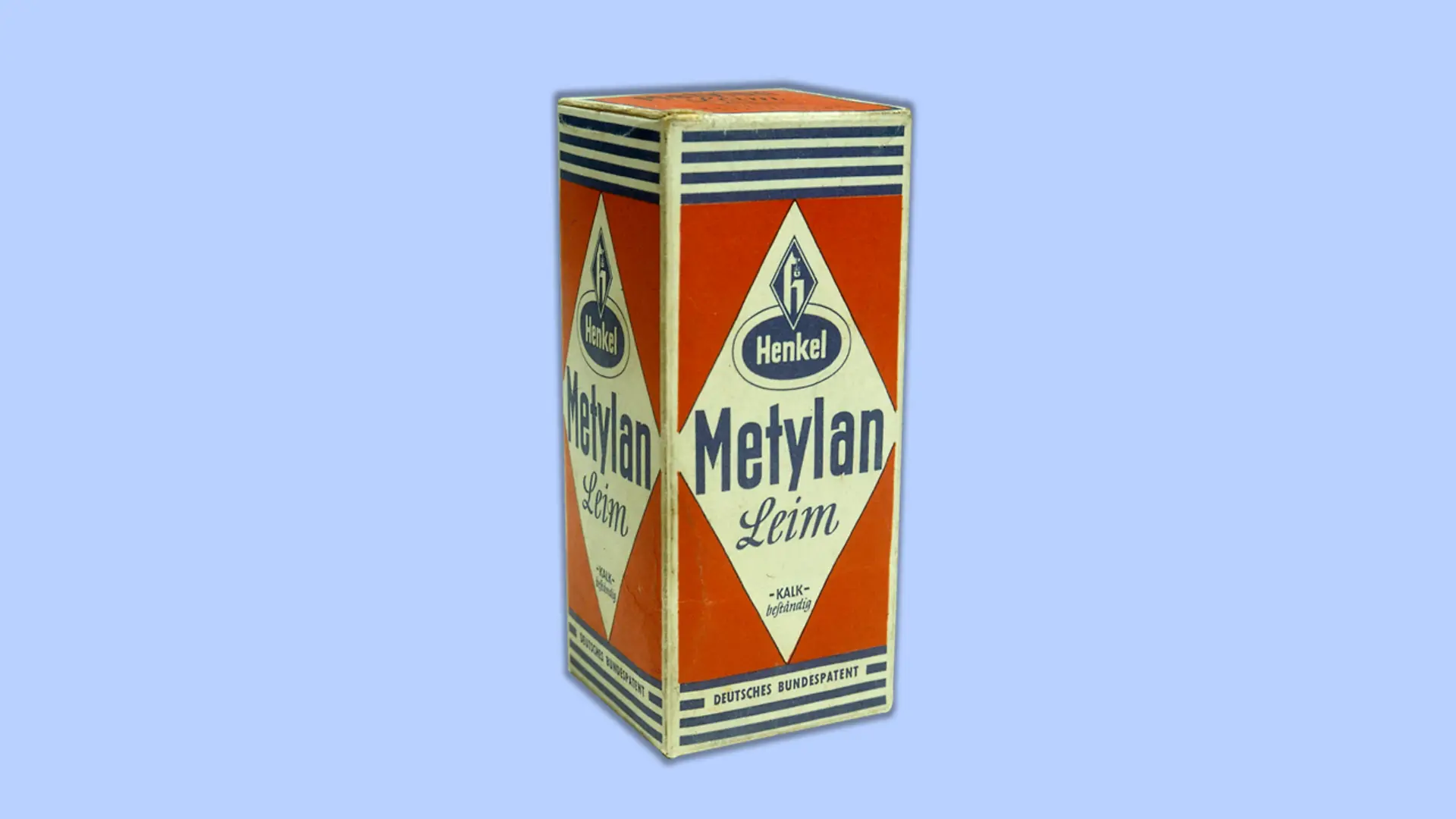 A red package of Metylan with blue stripes at the top and bottom. “Metylan Leim” (“Metylan Glue”) is written in the center of the package beneath a Henkel logo in blue. “Deutsches Bundespatent” (“German federal patent”) appears at the bottom of the package.