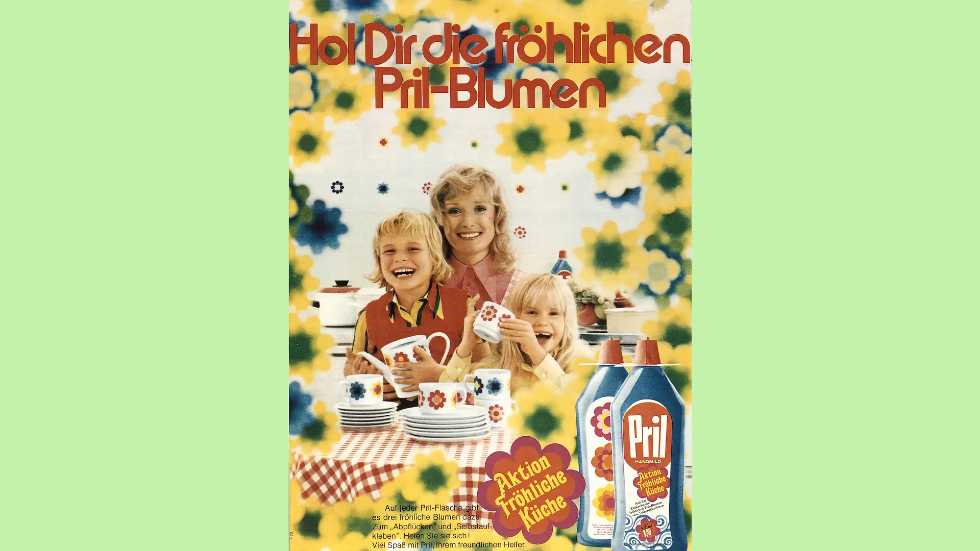 Advertisement for the “Fröhliche Küche (Merry Kitchen) campaign”. Blurred yellow flowers are placed around the entire edge of the ad. In the center of the ad, surrounded by the flowers, is a blonde woman sitting with two blonde children on her lap at a table covered with a red and white checkered tablecloth. All three are laughing happily into the camera. A clean set of dishes decorated with colorful Persil flowers is placed in front of them. The children are holding pieces of the set in their hands. The sentence “Get the cheerful Pril flowers” can be read at the top edge. Two bottles of Pril are also placed in the bottom right-hand corner.
