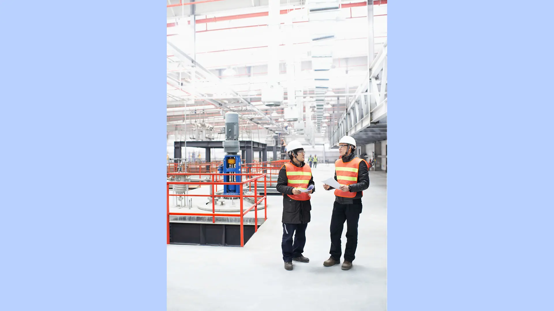 Two production workers stand in a huge, brightly lit factory hall at Henkel's Dragon Plant in China.