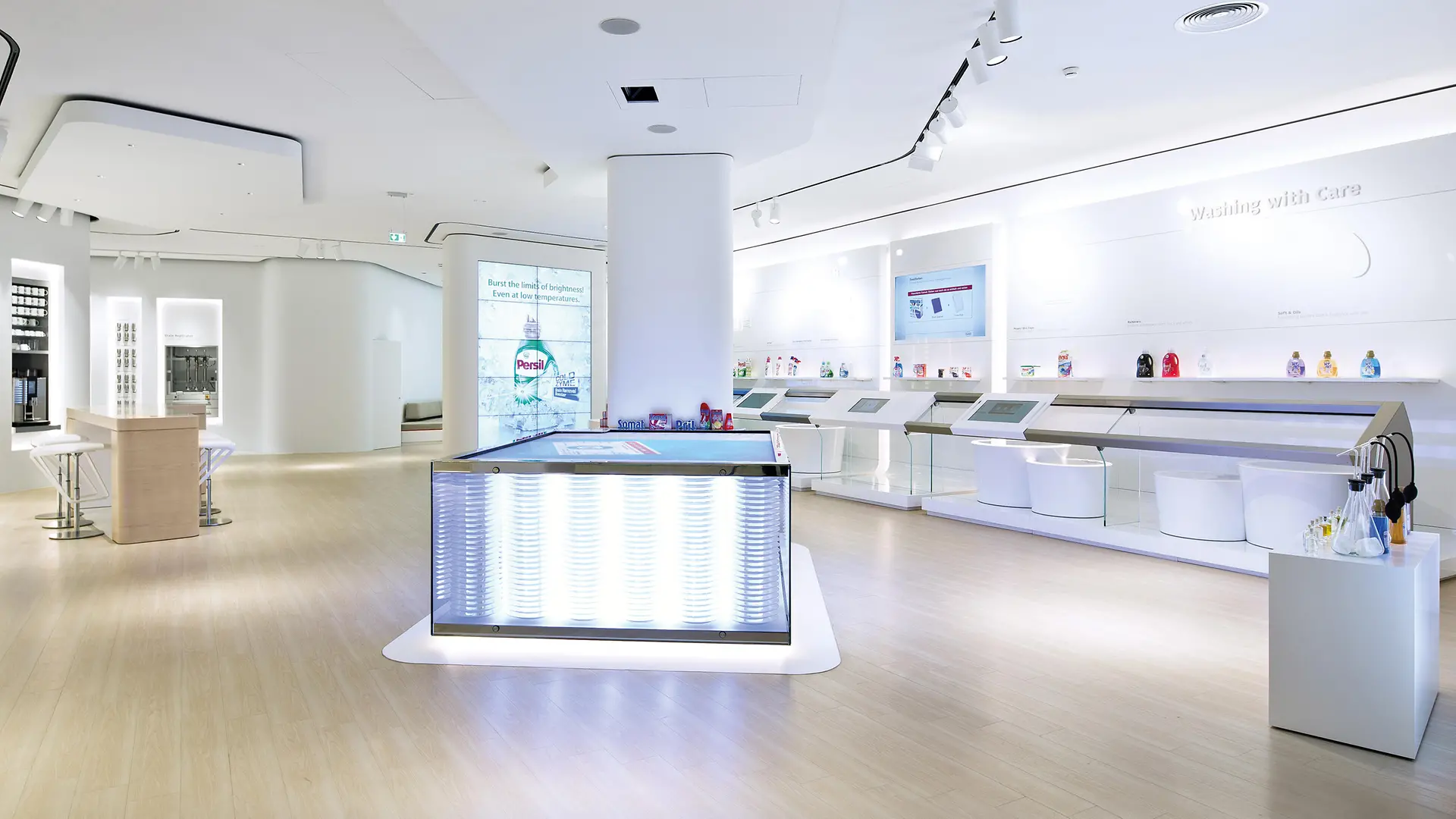 The interior of the Global Experience Center in Düsseldorf: a spacious, white showroom with touchscreens and various products on display.