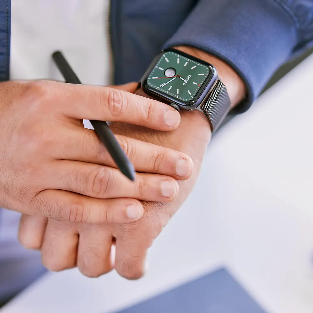 A close-up of a man looking at a black smartwatch on his left wrist.