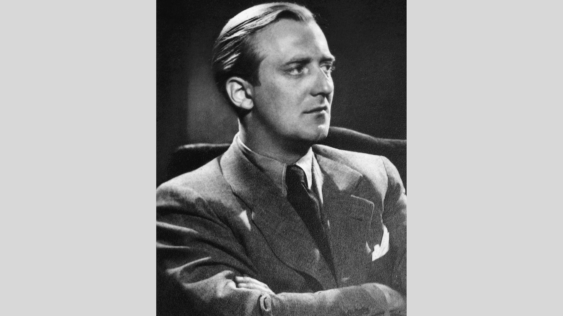 Black-and-white portrait of Werner Lüps. He is sitting in an armchair with his arms crossed, facing away from the camera and looking to the right past it.
