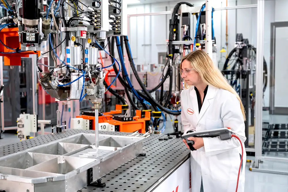 Scientist wearing a pendant closely observing the dispensing of thermal gap filler material.