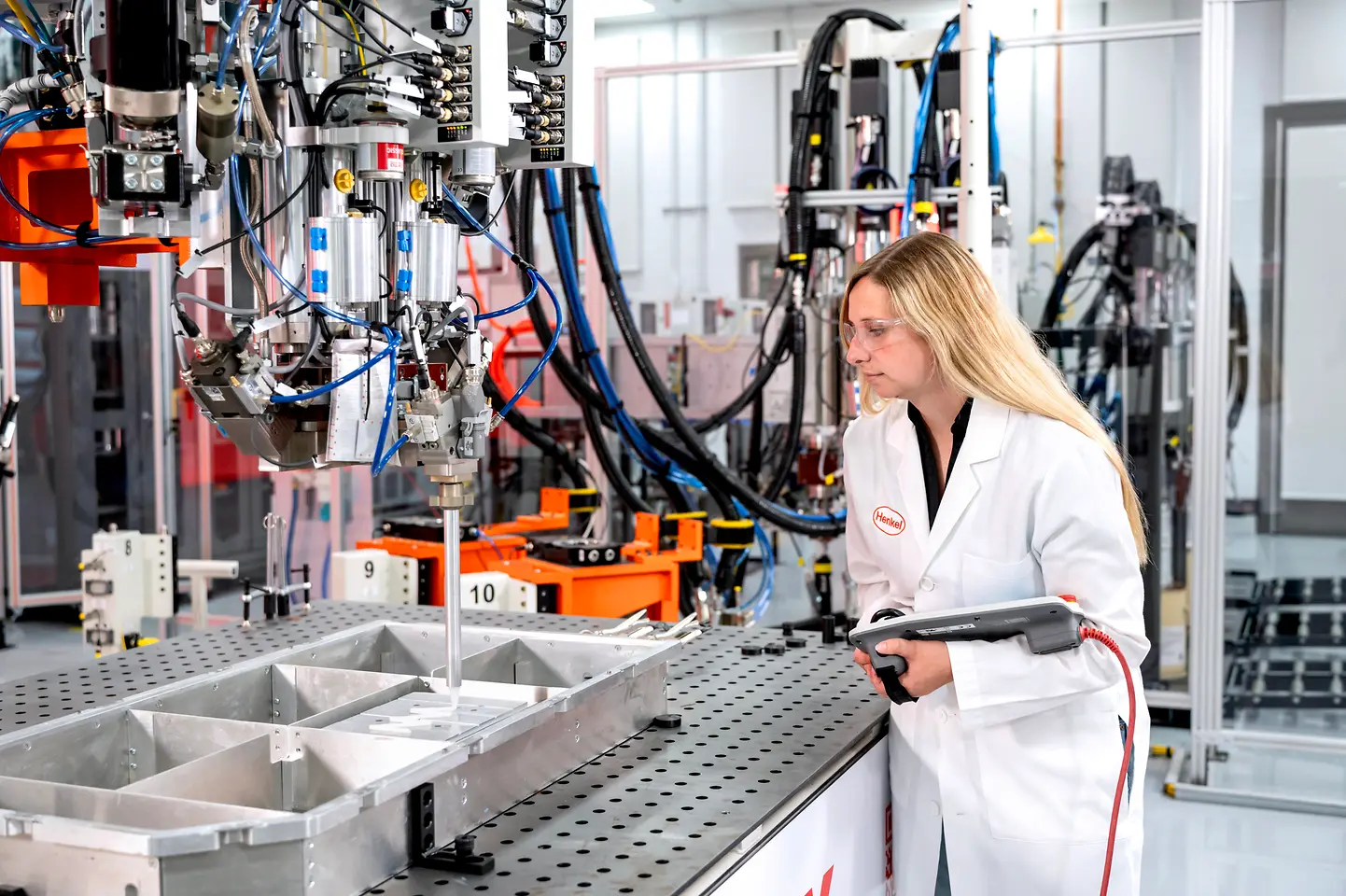 Scientist wearing a pendant closely observing the dispensing of thermal gap filler material.