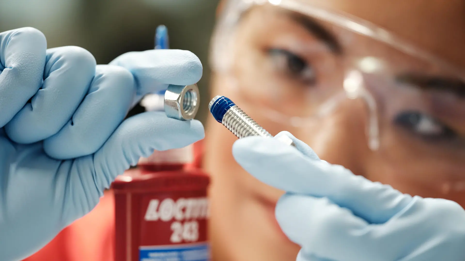 Close-up of a person applying Loctite adhesive to a bolt, illustrating precision and innovation in Henkel’s industrial adhesives business.