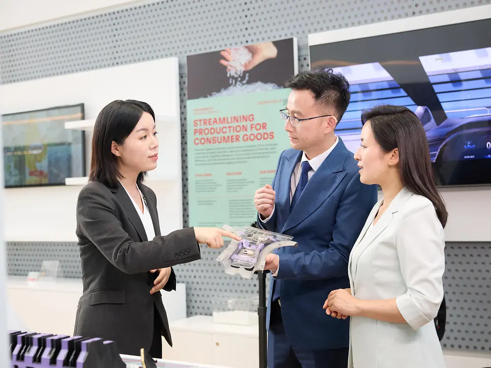 A woman explains a structural insert from a car to two customers in the permanent exhibition at the Inspiration Center Shanghai.