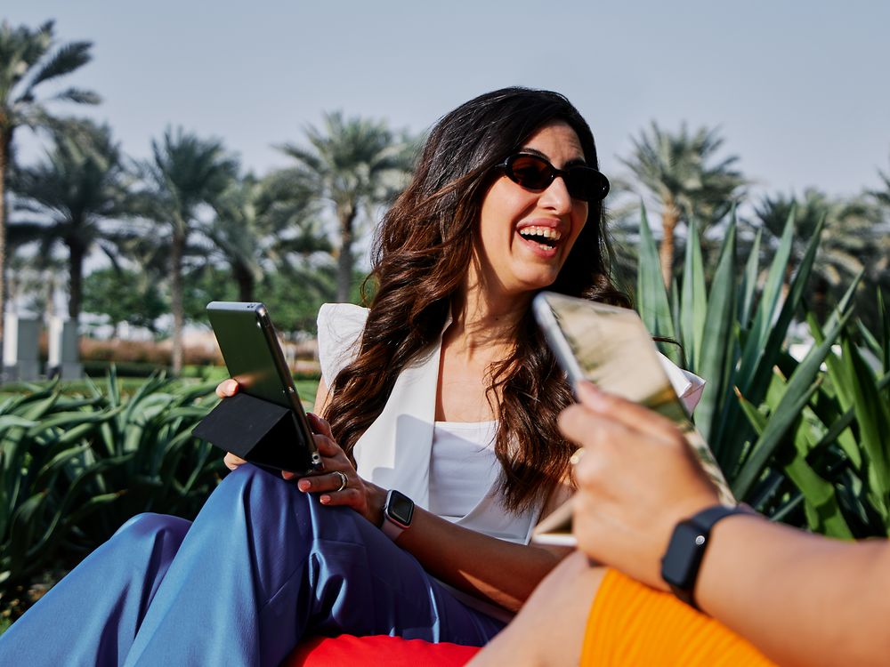 Woman working on a laptop outdoors in a sunny park, reflecting Henkel’s flexible work options and modern work culture.