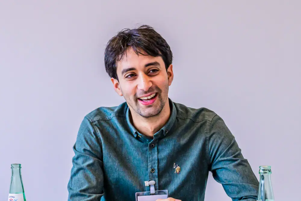 Senior leader in a professional meeting setting, seated across a table with documents during a strategy session at Henkel. 