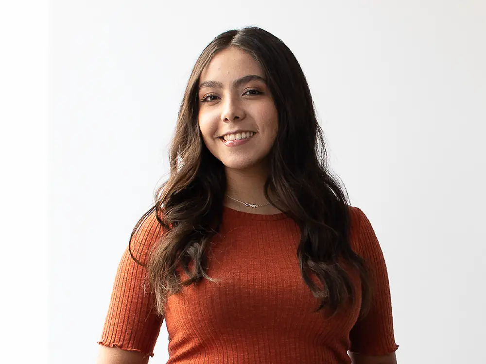 
Talent acquisition manager from Mexico wearing an orange ribbed short-sleeve top, sharing insights on how to stand out on LinkedIn. 