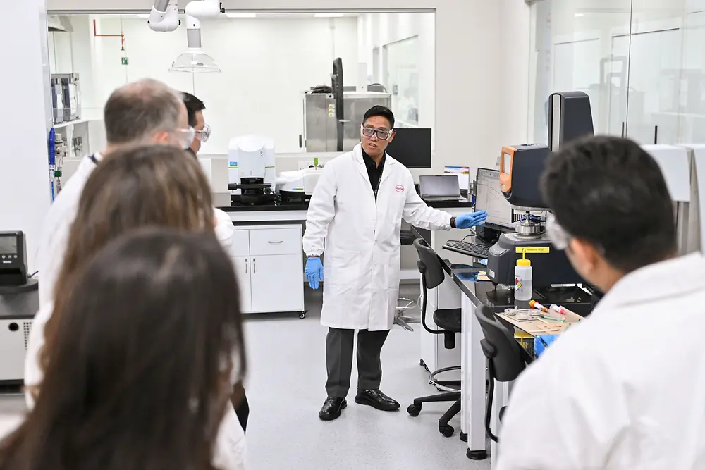 A man presenting to an audience in a lab. 