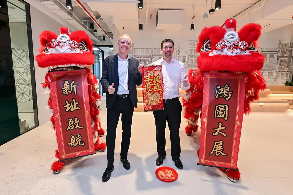 Two men standing next to lion dancers. 