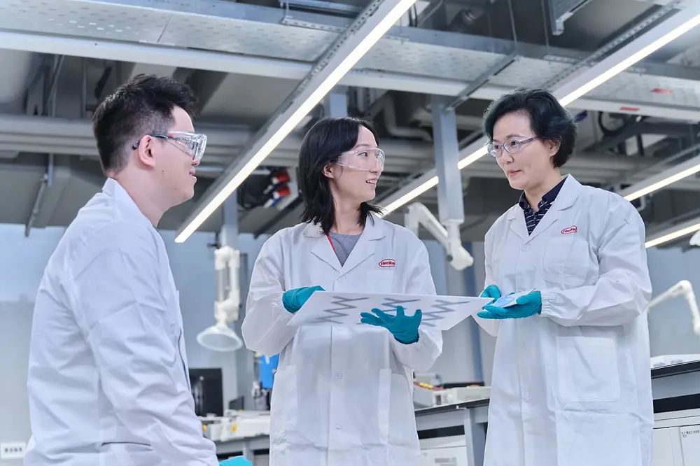 Two female scientists and one male scientist exchanging ideas in a laboratory.