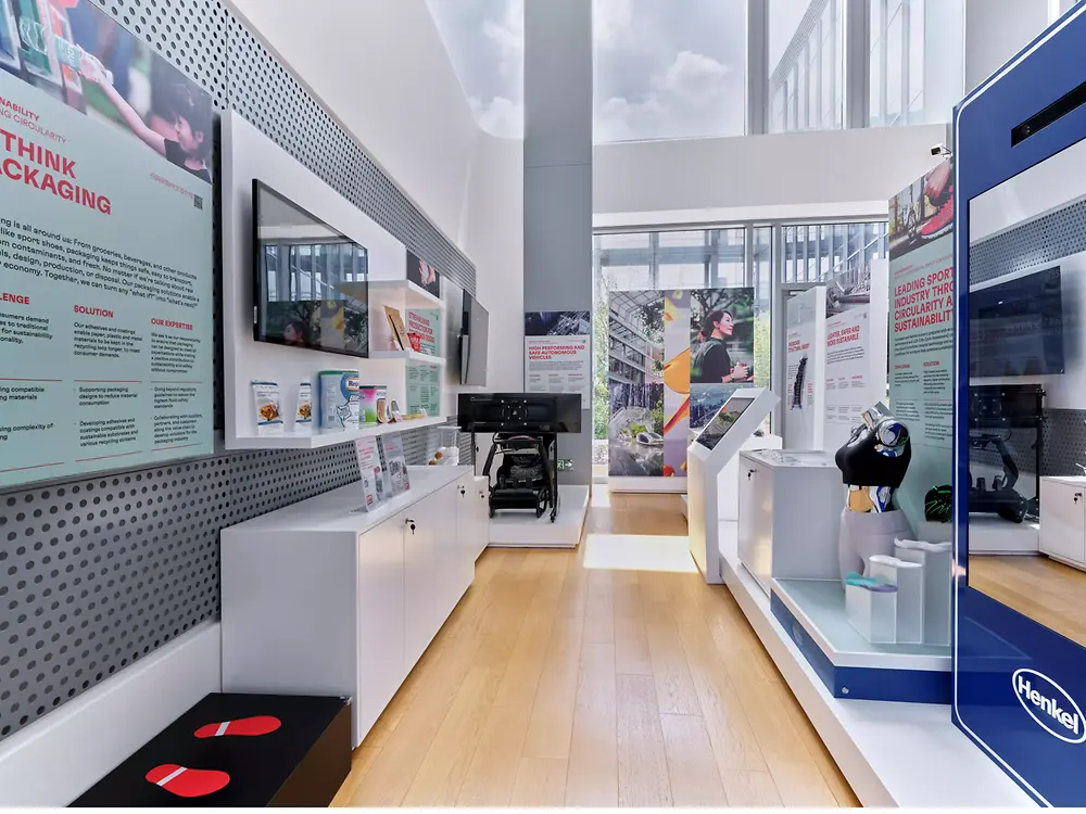 Innovative exhibit room with bright lighting, modern design, interactive screens, and product samples create a futuristic and eco-conscious atmosphere.