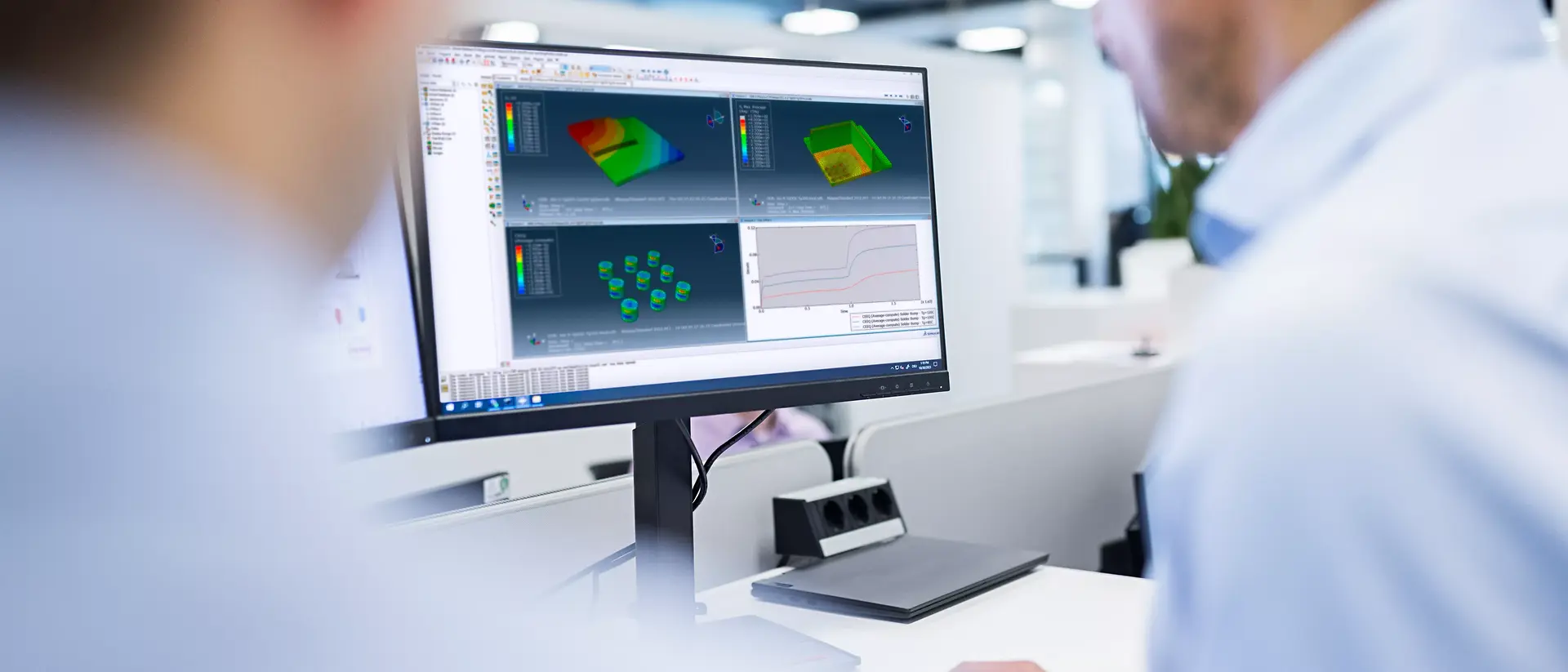 Two experts focus on a computer monitor displaying 3D modelling and simulation software in a modern office. The scene conveys concentration and collaboration.