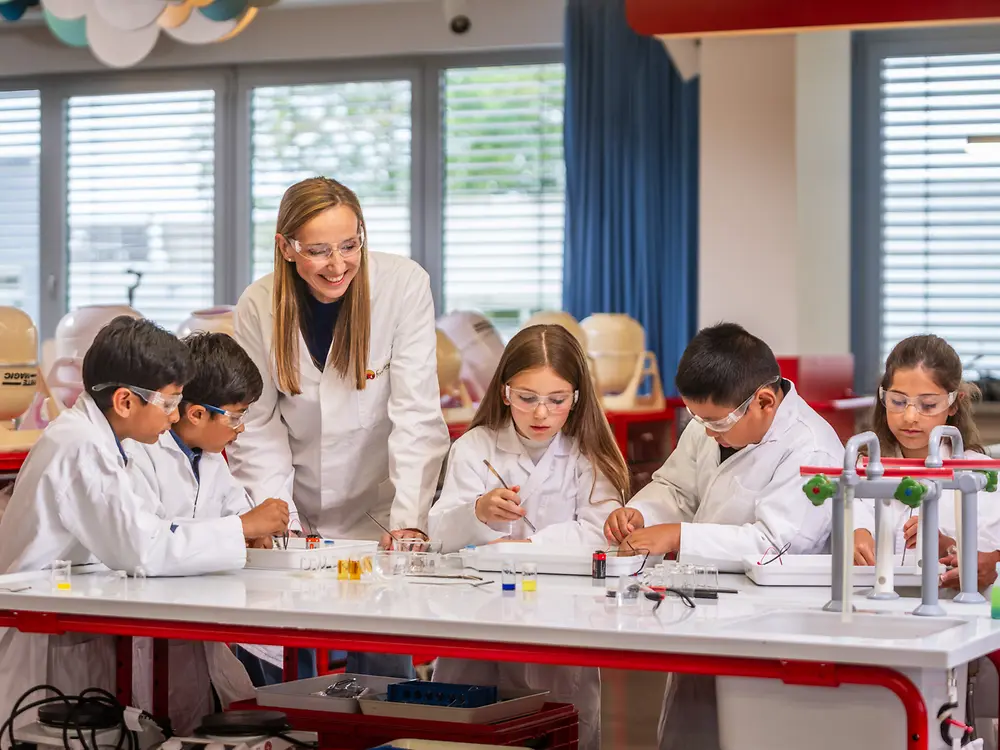 
Children in a science classroom conducting experiments with a teacher guiding them