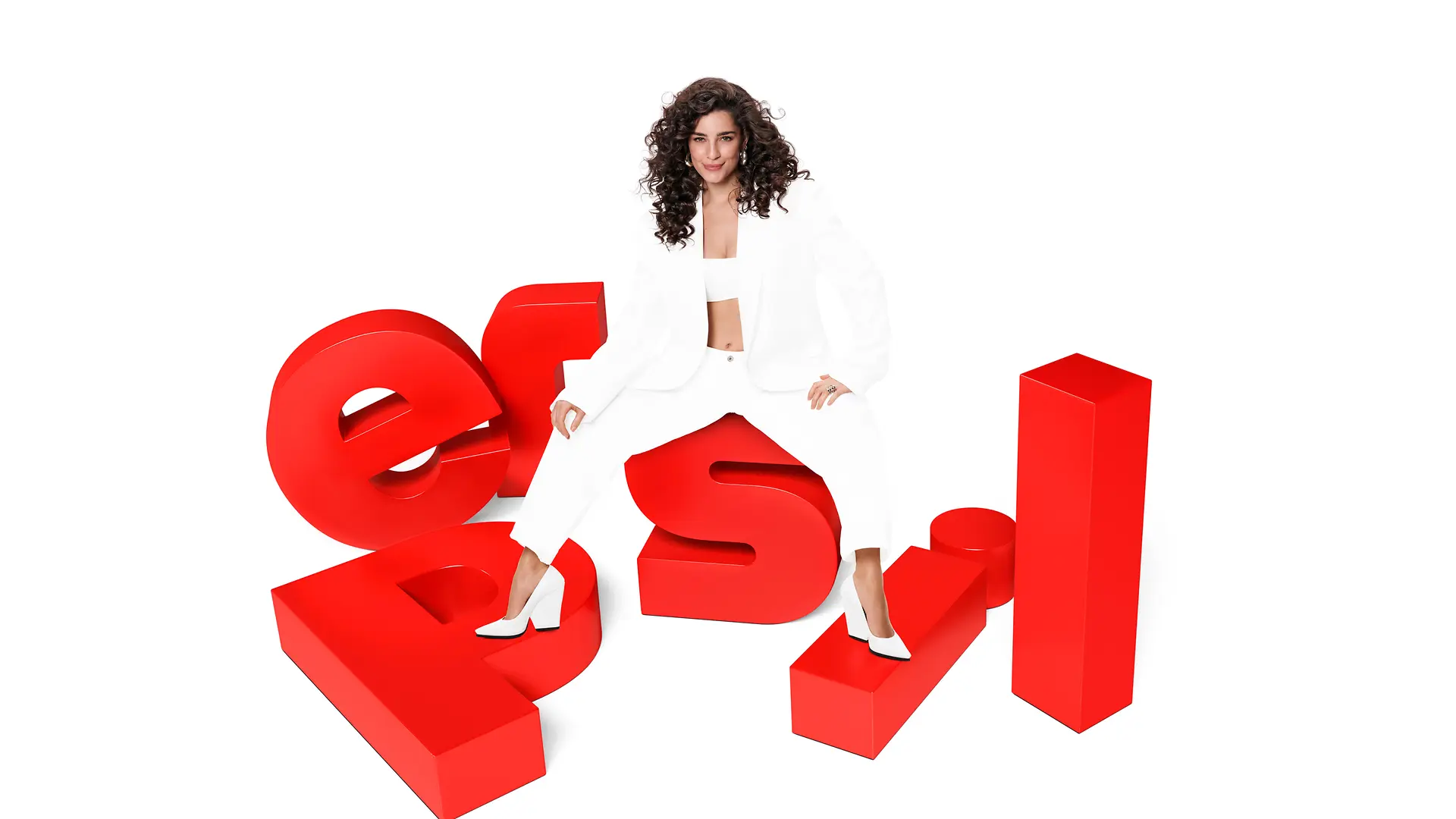 A woman with dark curly hair dressed in an all‑white outfit is seated on oversized, three‑dimensional red letters spelling “Persil.” The figure is positioned centrally against a plain white background.