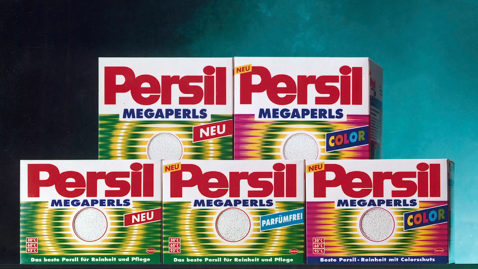 A row of Persil Megaperls detergent packages are displayed. The packages show different variants, including standard and Color versions, all featuring the Persil logo, bold typography, and the distinctive pearl‑based detergent branding.