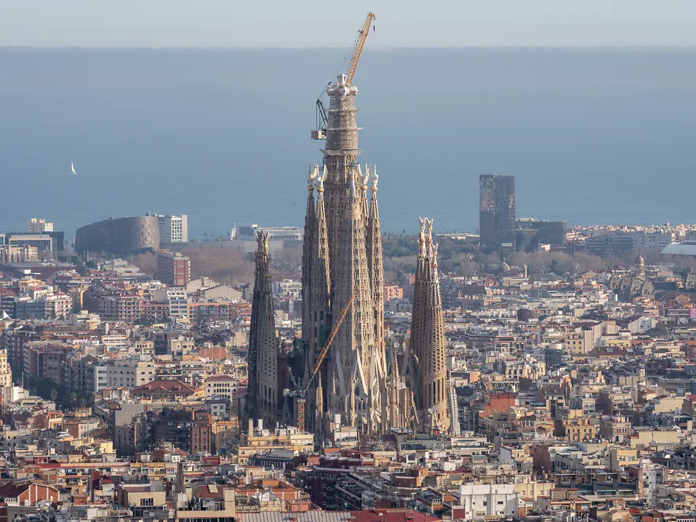 Cranes operating on the central towers with the Mediterranean Sea in the background