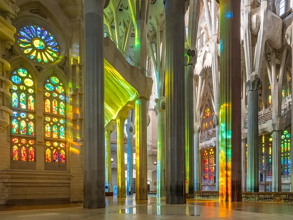 Interior space with stained glass windows casting colored light across the columns