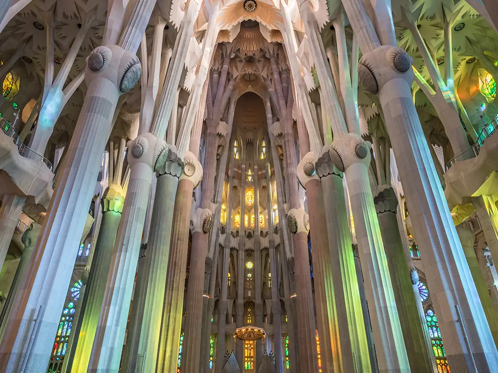 Interior view of the Sagrada Familia with tall columns and vaulted ceiling structure