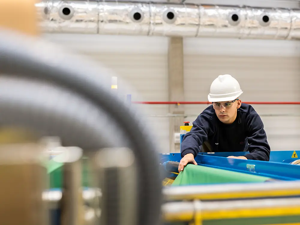 
Operator adjusting material on filmer line