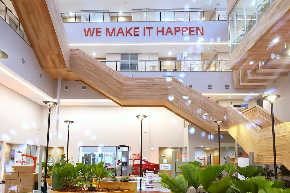 Modern atrium of the Inspiration Center Jundiaí with plants and the slogan “WE MAKE IT HAPPEN”.