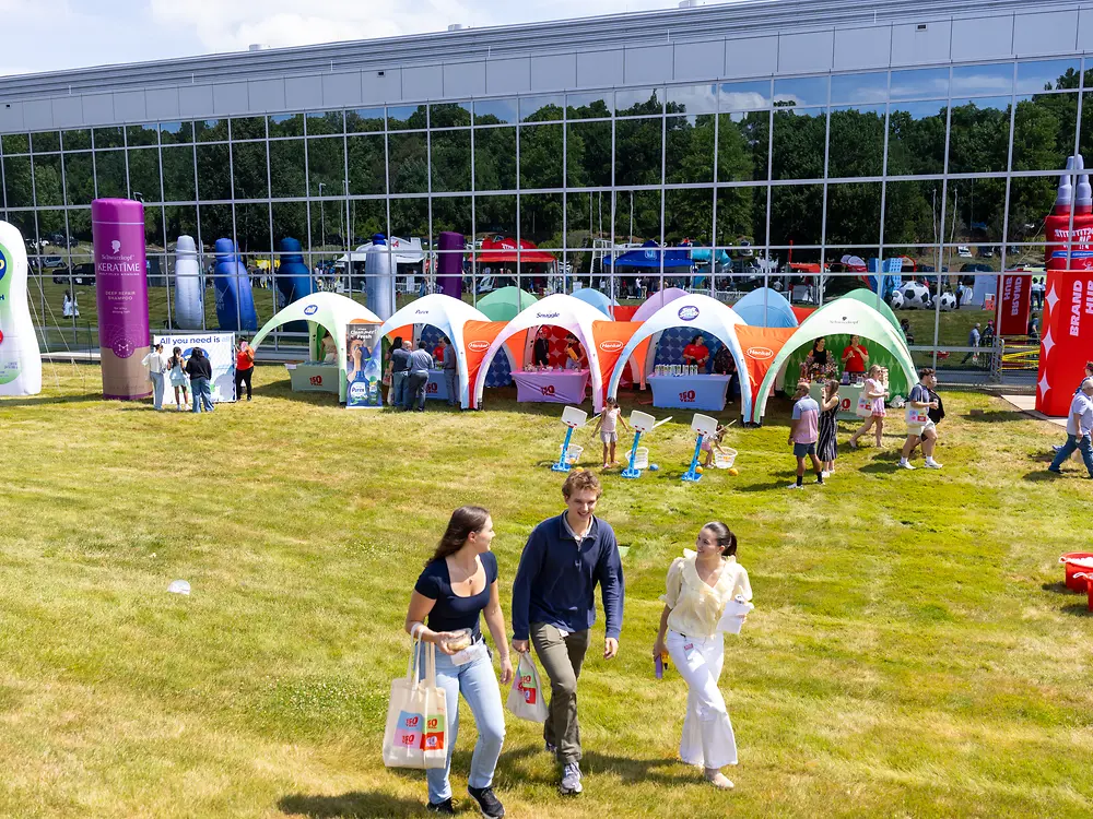Many adults and children gathered outdoors at a festival site with tents and event activities.