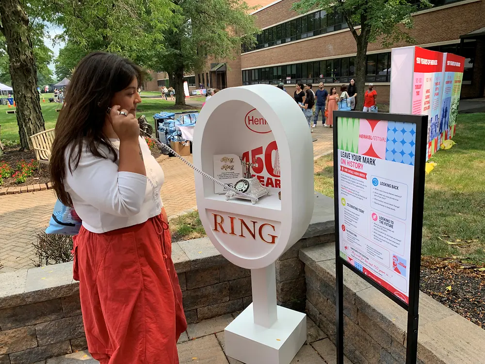 An employee uses a vintage-style telephone as part of an interactive exhibit showcasing Henkel’s 150-year history.