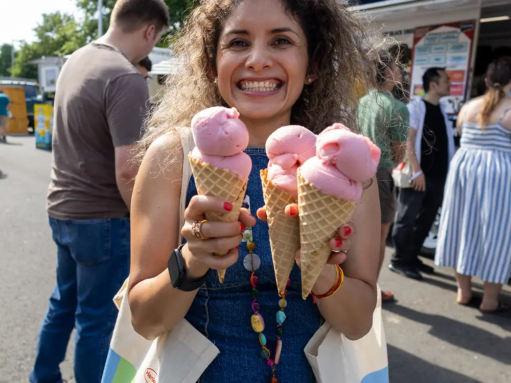 An employee holds several ice cream cones in front of an ice cream truck during a Henkel anniversary celebration.