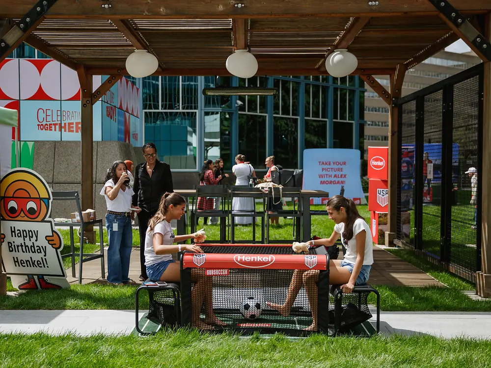 Employees take part in a table football activity at an outdoor Henkel anniversary event.