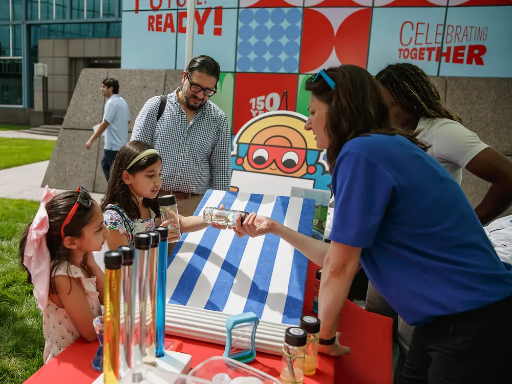 Children and employees take part in an interactive activity booth at a Henkel anniversary event.